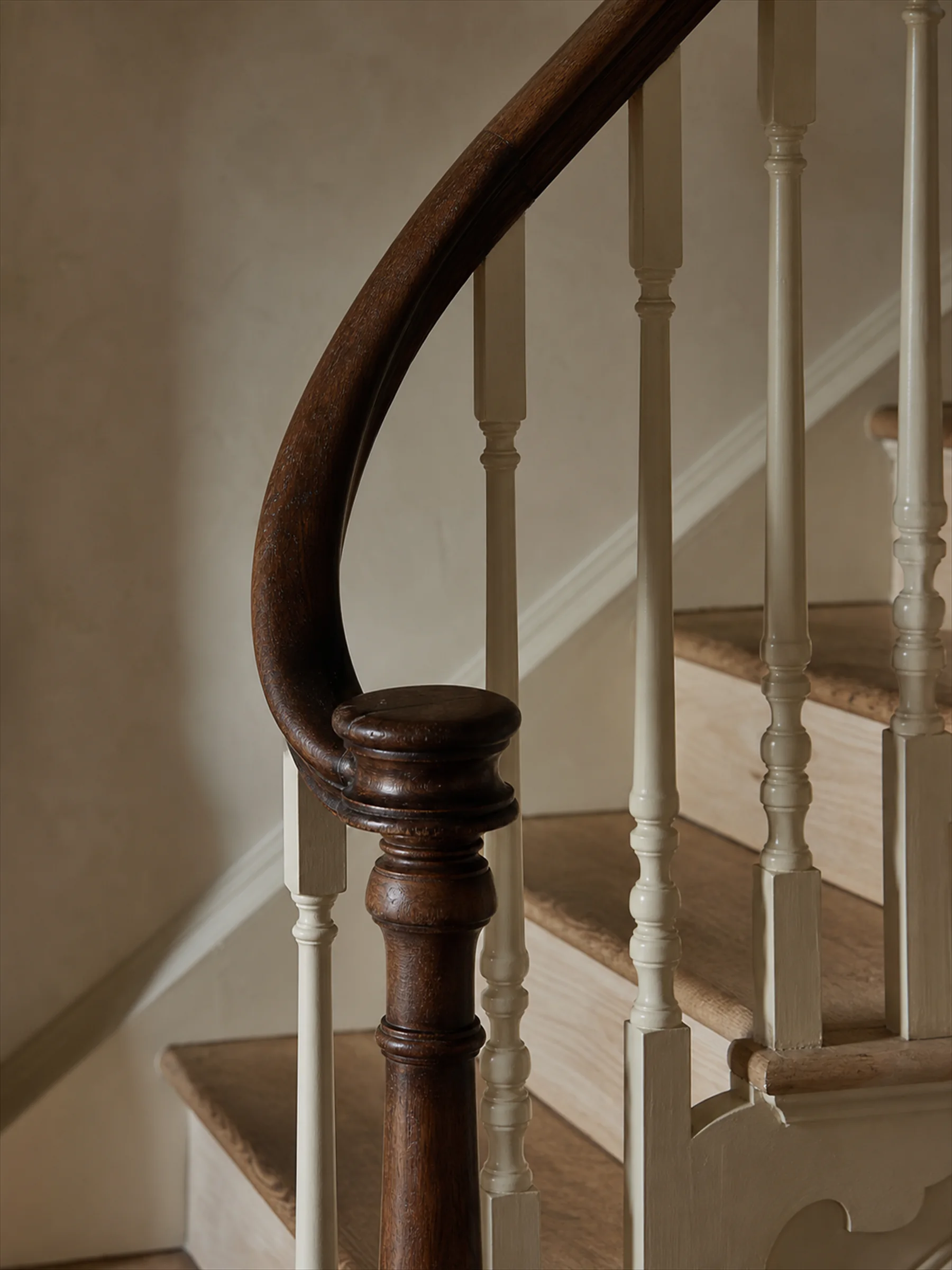 A curved oak handrail and painted spindles on a period staircase